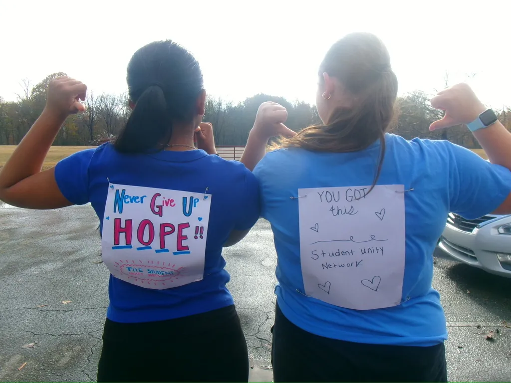Volunteers flexing to show messages of hope on their shirts
