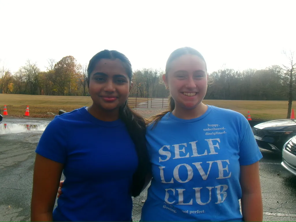 Two volunteers smiling in matching blue shirts